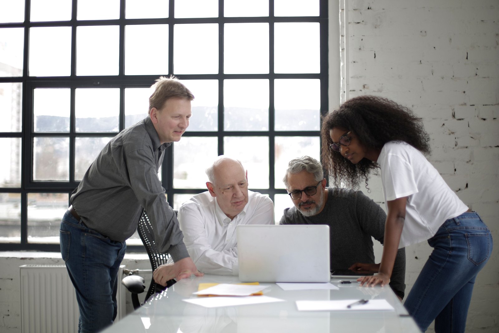 Colleagues collaborating around a laptop in a bright workspace