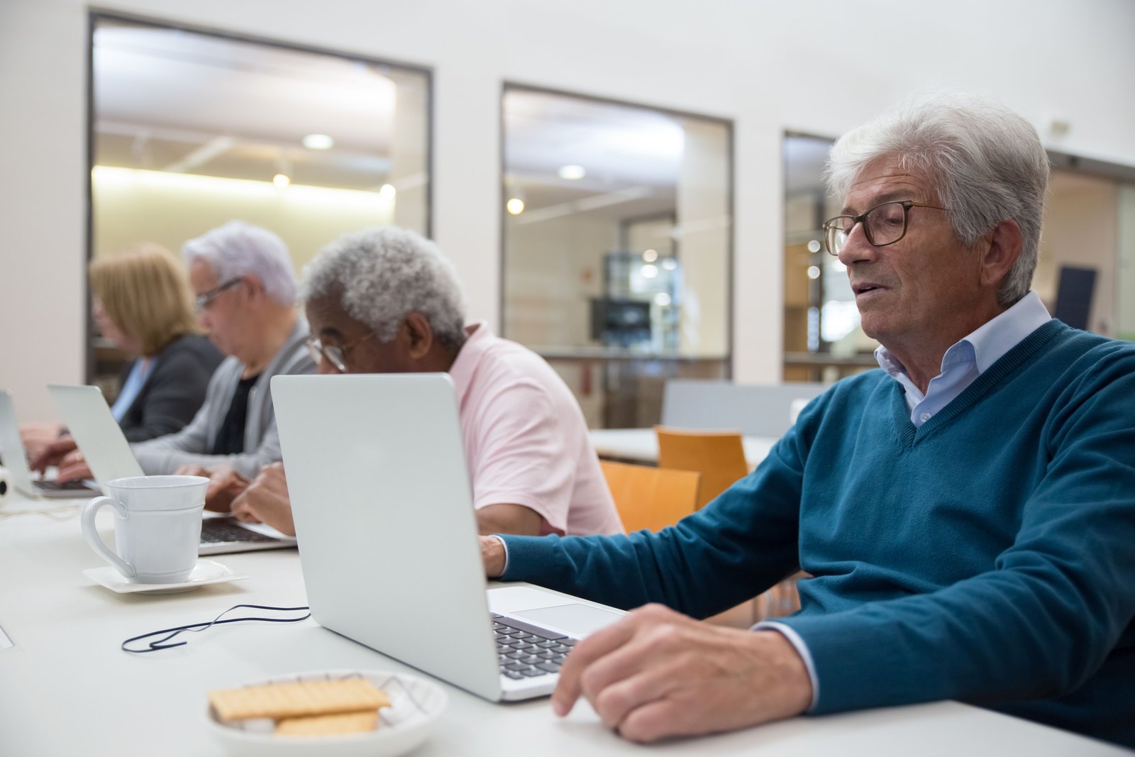 Inclusive technology education: adult learners of every age at laptops Adult learners of all ages practicing on laptops in a community class
