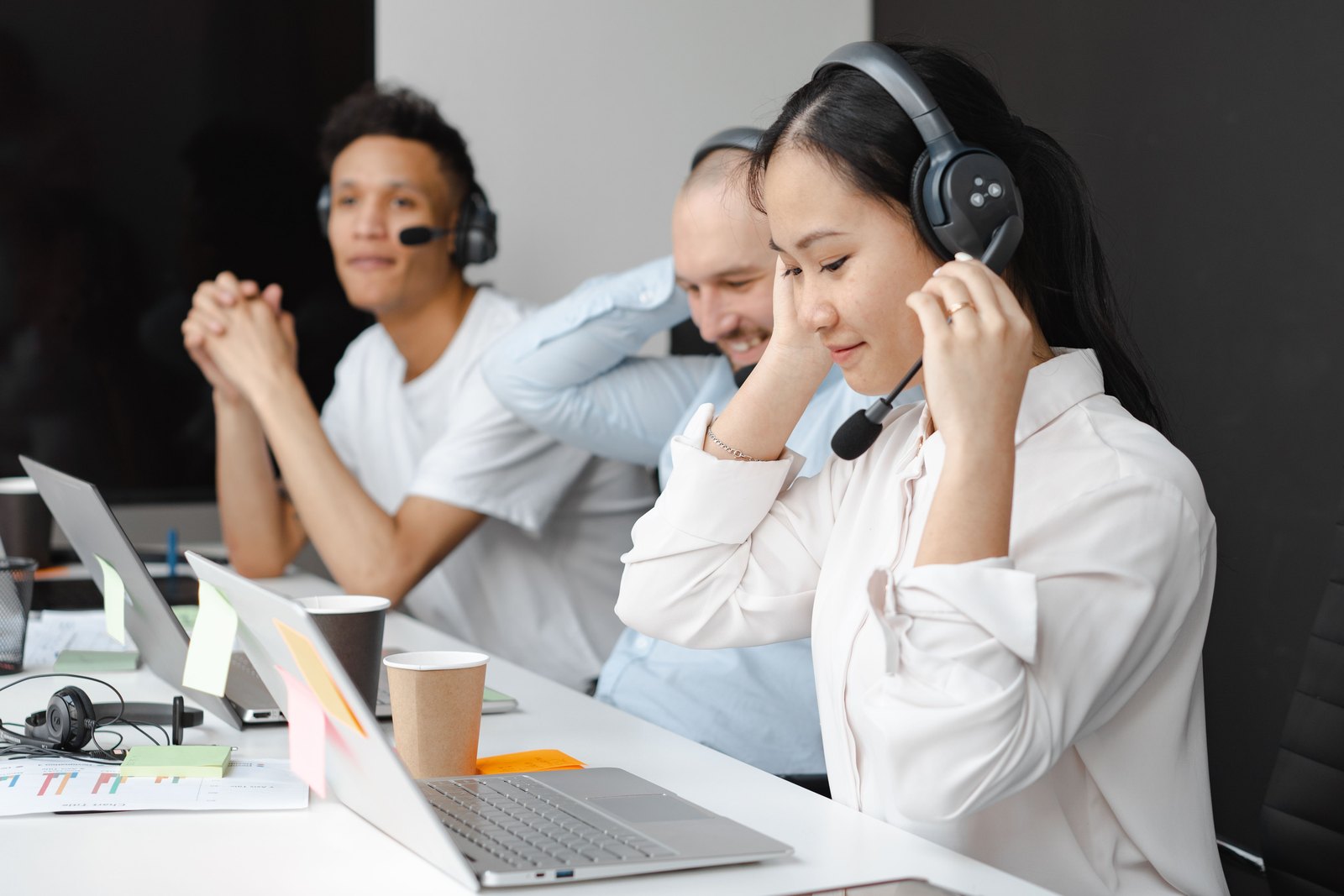 Support team member adjusting her headset at a busy help desk